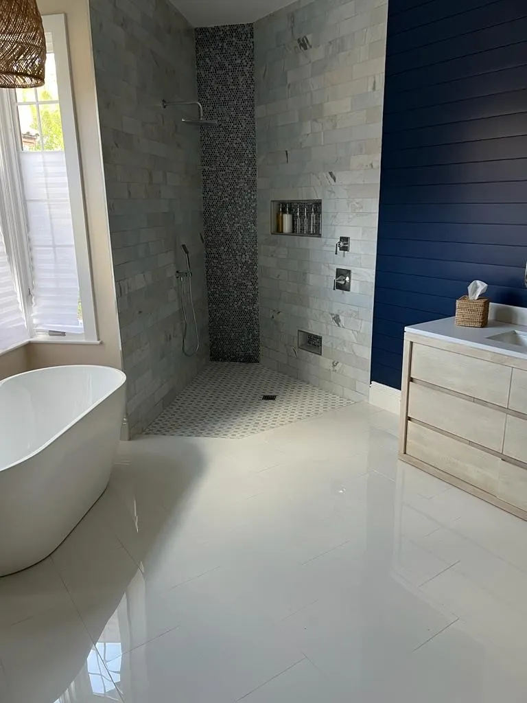 Luxurious bathroom combining marble subway tile shower, navy blue shiplap accent wall, and white freestanding bathtub