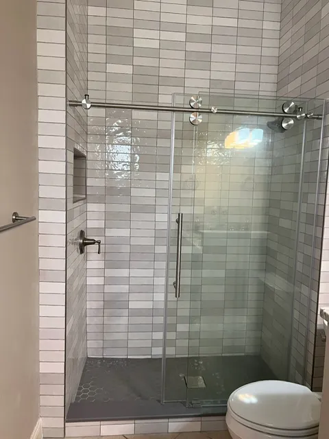 Clean bathroom design with white subway tile, glass shower door, and contemporary fixtures