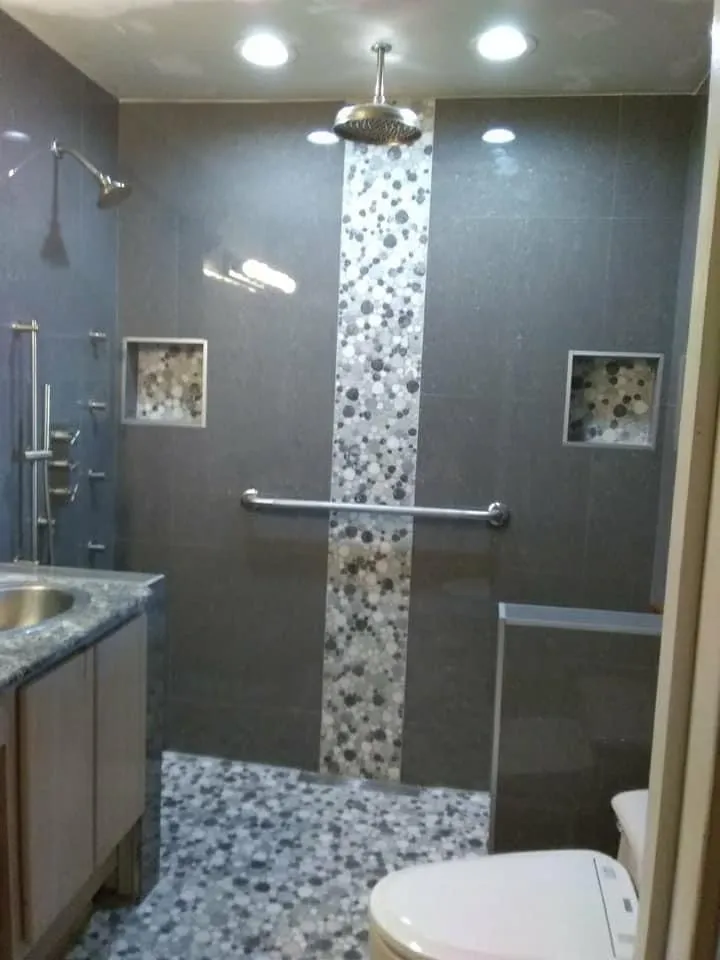 Sophisticated bathroom with wood-look tile, pebble accent stripes, modern lighting, and freestanding tub