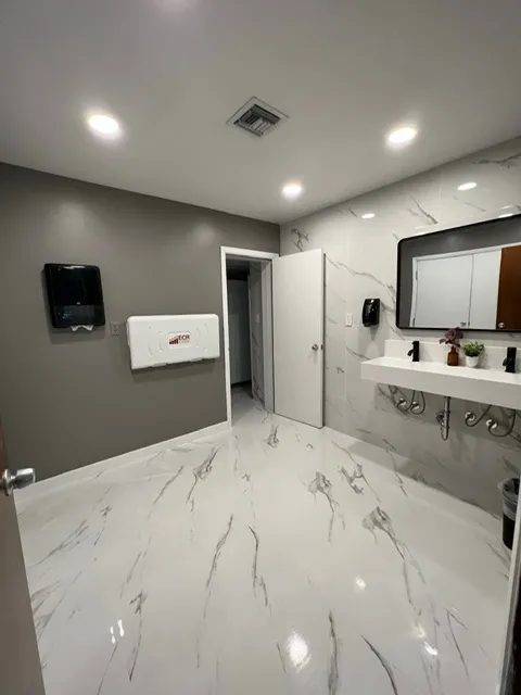 Commercial-style bathroom with marble wall tiles, modern floating vanity, and clean contemporary design