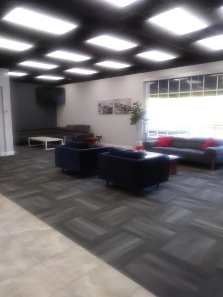 Commercial lounge space with modern dropped ceiling lighting, contemporary seating, and professional design
