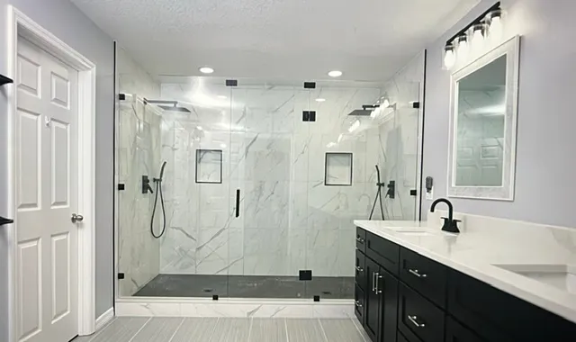 Spacious dual shower with marble wall tiles, chrome fixtures, built-in niches, and contemporary design