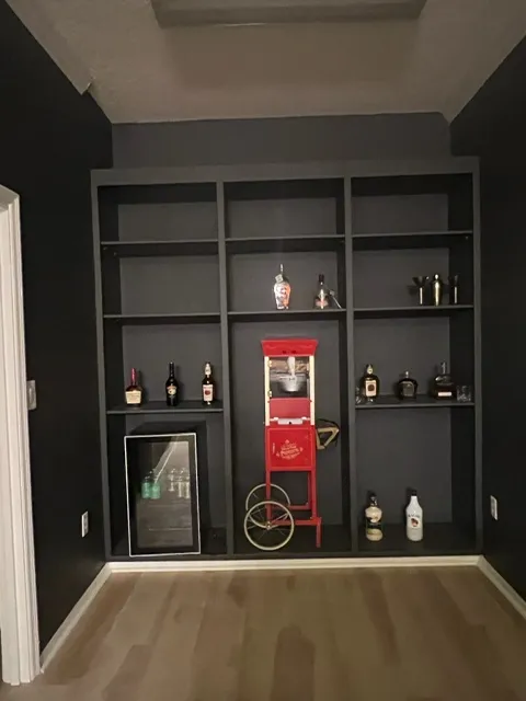 Entertainment room featuring dark built-in shelving, vintage popcorn machine, and well-organized bar area