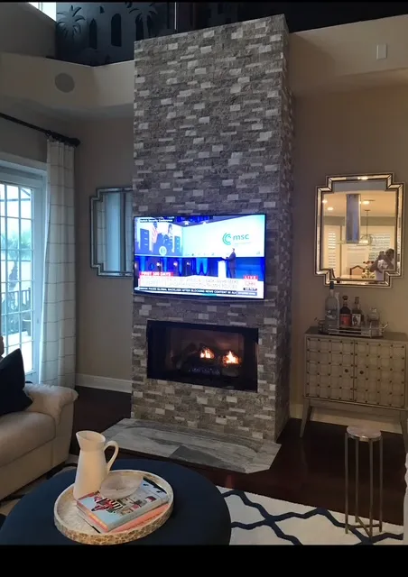 Elegant living room featuring natural stone fireplace, built-in cabinetry, and warm contemporary design