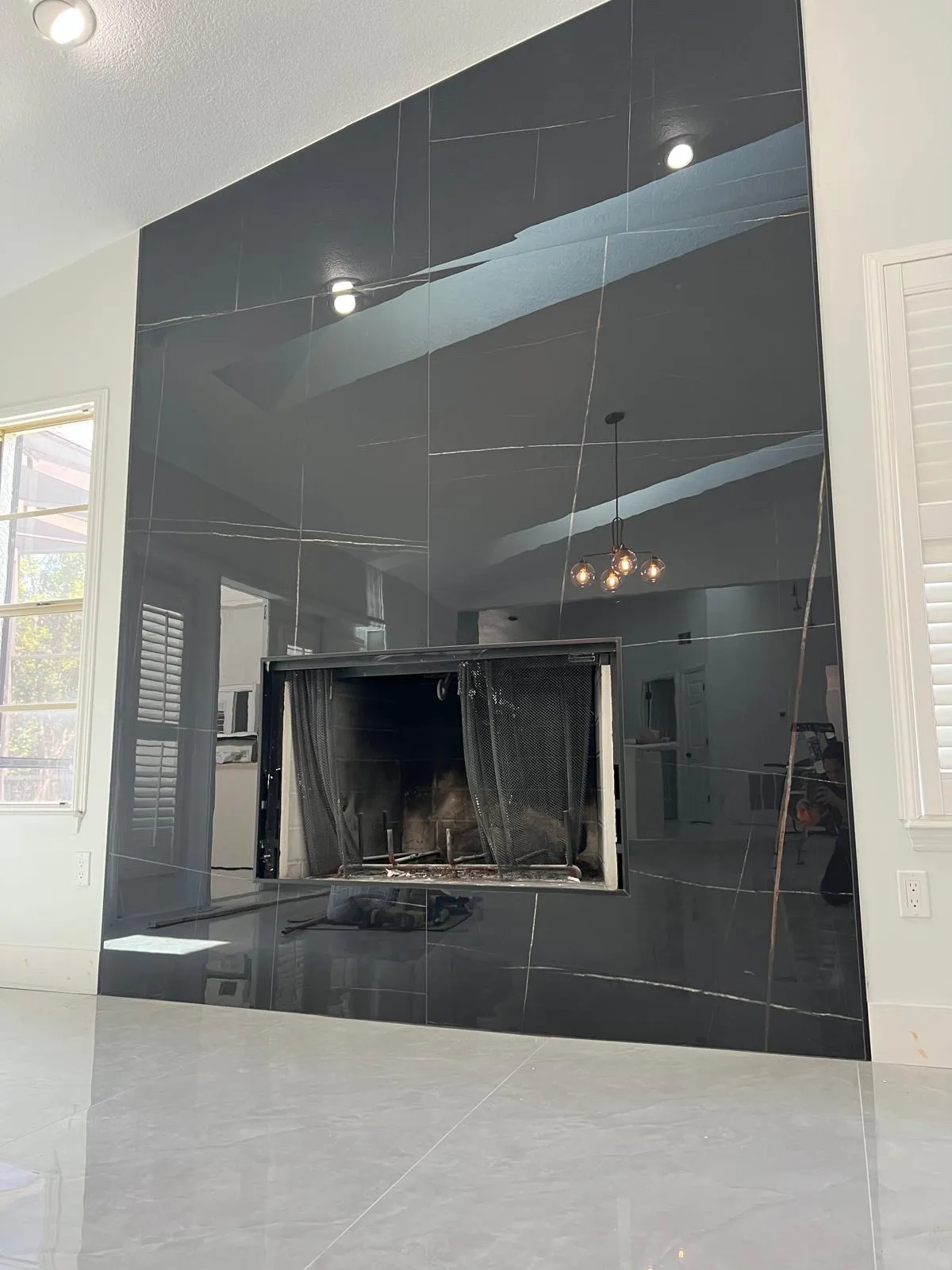 Dramatic modern fireplace with large dark tiles, clean lines, and contemporary design with pendant lighting