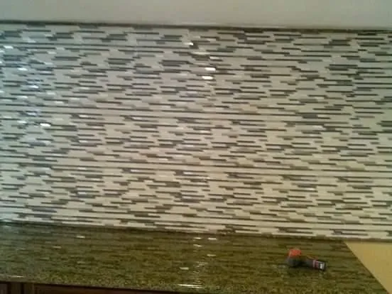 Close-up of mosaic tile backsplash installation showing detailed craftsmanship and pattern work