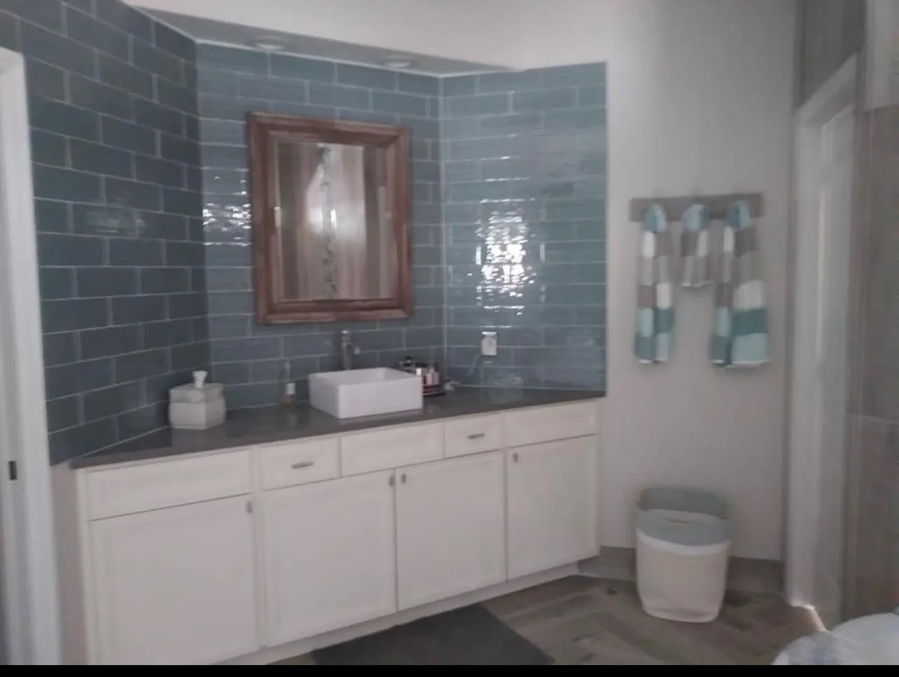 Sophisticated powder room with blue subway tile, white vanity, and decorative mirror