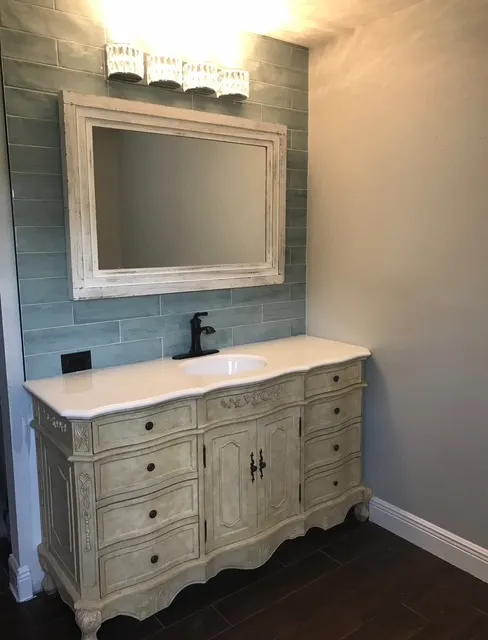 Charming powder room with vintage-style vanity, blue subway tile backsplash, and elegant fixtures
