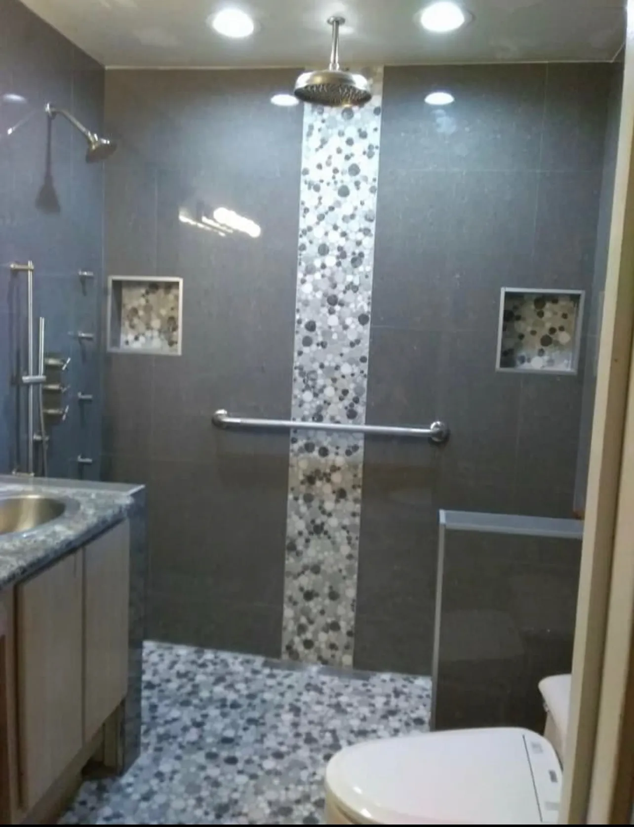 Modern shower design featuring pebble tile accent stripe and contemporary fixtures