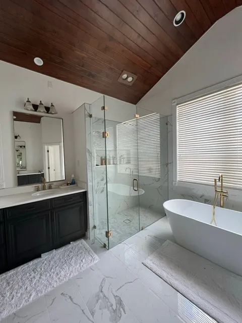 Sophisticated bathroom design with rich wood plank ceiling, large glass shower enclosure, and elegant freestanding bathtub