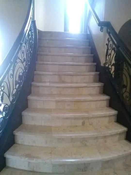 Elegant curved staircase with marble steps and ornate wrought iron railings